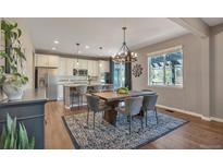 Open concept kitchen with stainless steel appliances, island seating, and connected dining area with stylish chandelier at 7665 Grady Cir, Castle Rock, CO 80108