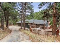 Charming home exterior with a spacious deck surrounded by a lush forest at 94 Spring Ln, Boulder, CO 80302