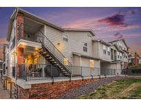 Exterior view of a modern townhouse featuring a private patio, stairs, and brick foundation at sunset at 1646 S Deframe St # B8, Lakewood, CO 80228