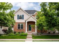 Charming two-story home with brick facade, manicured lawn, and lush greenery, creating a welcoming curb appeal at 8122 E 6Th Pl, Denver, CO 80230