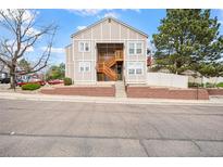 A two-story condo building with a wooden staircase and brick foundation offers charming curb appeal at 9677 W Chatfield Ave # E, Littleton, CO 80128