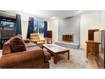 Cozy living room featuring a brick fireplace, plush furniture, and ample natural light from the window at 3161 S Kalispell St, Aurora, CO 80013