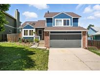 Charming two-story home with brick and blue siding, complemented by a well-manicured lawn and a two-car garage at 3593 S Gibralter Cir, Aurora, CO 80013