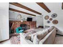 Cozy living room with brick fireplace, wood beams and decor accents at 3593 S Gibralter Cir, Aurora, CO 80013