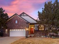 Charming brick home with a well-maintained lawn and an inviting red front door under a colorful sky at 8099 Sabino Ln, Castle Rock, CO 80108