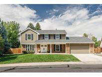 Two-story house with brick and siding, showcasing a charming front porch and well-manicured lawn at 8875 E Phillips Pl, Centennial, CO 80112