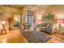 Bright living room with hardwood floors, modern furniture, and an open balcony with views at 275 S Harrison St # 409, Denver, CO 80209