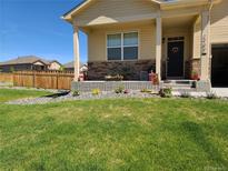 Charming home featuring a well-manicured lawn, stone accents, and inviting front porch at 1799 Jade Ave, Brighton, CO 80603