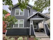 Beautiful two-story home with gray siding, white trim, landscaped yard and a covered front porch with an outdoor seating area at 2857 Xanthia Ct, Denver, CO 80238