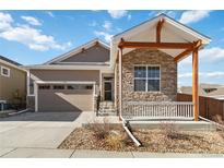 Charming single-Gathering home with stone accents, a covered porch, and a two-car garage at 11482 Colony Loop, Parker, CO 80138