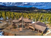 Stunning home with stone and tan siding, mountain views, and a three-car garage nestled among towering trees at 11405 Conifer Ridge Dr, Conifer, CO 80433
