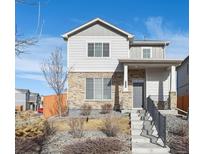 Charming two-story home with stone accents, a welcoming porch, and landscaped yard at 6792 Longpark Dr, Parker, CO 80138