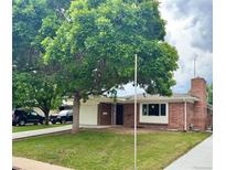 Charming brick home with a well-manicured lawn, mature trees, and an attached one-car garage at 1815 S Monroe St, Denver, CO 80210