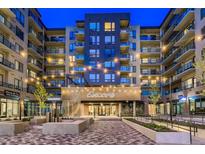Modern apartment complex featuring string lights and brick facade at twilight at 20 Wilcox # 421, Castle Rock, CO 80104