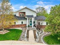 Charming two-story home with a manicured lawn, landscaped garden, and inviting walkway leading to a teal front door at 2161 Elmwood St, Berthoud, CO 80513