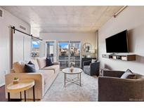 Bright living room with a barn door, hardwood floors, a comfortable sofa and a balcony with city views at 1475 Delgany St # 306, Denver, CO 80202