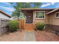 Charming brick home featuring a welcoming entrance with wooden stairs and landscaped front yard at 3679 Ivanhoe St, Denver, CO 80207