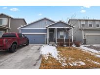 Charming two-story home featuring a covered porch, attached garage, and well-maintained front yard at 309 Spruce St, Bennett, CO 80102