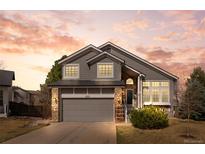 Charming two-story home featuring gray siding, stone accents, and a well-maintained front yard at 8635 Cresthill Ln, Highlands Ranch, CO 80130