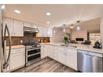 Updated kitchen features white cabinets, stainless appliances, and an open layout to the adjacent living room at 2061 S Worchester Way, Aurora, CO 80014