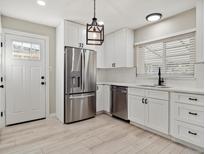 Modern kitchen featuring stainless steel appliances, white cabinets, and hardwood floors at 1475 S Eaton St, Lakewood, CO 80232