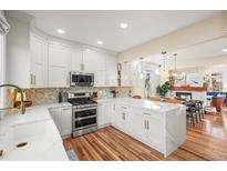 Modern white kitchen featuring stainless steel appliances, marble countertops, and stylish lighting fixtures at 2801 W 23Rd Ave, Denver, CO 80211