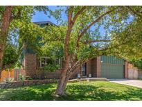 Charming home boasts a brick exterior, lush green lawn, mature tree, and well-maintained landscaping at 9400 W Burgundy Ave, Littleton, CO 80123