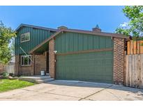 Charming home with a brick and green facade, complemented by a well-maintained lawn and an attached two-car garage at 9400 W Burgundy Ave, Littleton, CO 80123