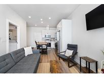 Open living room with grey sofa and chairs, wood coffee table, and kitchen island at 1208 Quitman St # 303, Denver, CO 80204