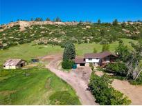 Beautiful home in a rural setting with a rock outcropping backdrop at 1151 Castlewood Pl, Franktown, CO 80116