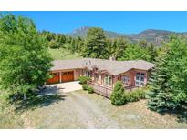 Charming ranch-style home with a large deck, wooden garage doors, and mountain views at 153 Gold Run Trl, Idaho Springs, CO 80452