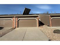 Row of garages featuring brick accents, concrete driveways, and solar panels on garage roof at 6921 S Bryant St, Littleton, CO 80120