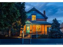 Charming two-story brick home with a covered front porch, black iron fence and inviting curb appeal at twilight at 2445 W 39Th Ave, Denver, CO 80211