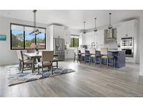 Bright, open kitchen with a large island, modern appliances, and a dining area with large windows at 3343 S Newcombe St, Lakewood, CO 80227