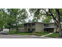 Two-story tan apartment building featuring a grassy lawn, bench and several large leafy trees at 755 S Clinton St # 1B, Denver, CO 80247
