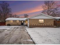 Brick ranch home with a snow-covered front yard and driveway at 460 Iola St, Aurora, CO 80010