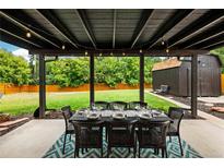 Covered patio dining area features a long table set for ten with an adjacent lush green lawn and shed at 7256 S Broadway, Centennial, CO 80122