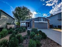 Inviting home featuring a charming front yard with mature landscaping and a two-car garage at 6365 Xavier Ct, Arvada, CO 80003