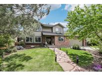 Charming two-story home with a well-manicured lawn, mature trees, and a stone pathway leading to the entrance at 8291 S Krameria Way, Centennial, CO 80112