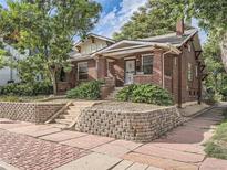 Charming brick home featuring a cozy front porch, manicured landscaping, and classic architectural details at 2303-2305 W 32Nd Ave, Denver, CO 80211