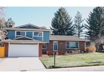 Charming two-story home featuring brick and blue siding with a well-manicured front lawn and driveway at 5404 W Rowland Pl, Littleton, CO 80128