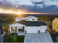 Beautiful two-story home with white siding and a three-car garage, showcasing a lovely sunset view at 1601 Mariah Ln, Erie, CO 80516