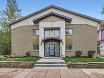 Two-story apartment building with brick and stucco, featuring a covered entrance and manicured landscaping at 2460 W Caithness Pl # 105, Denver, CO 80211
