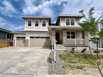 Inviting two-story home featuring a three-car garage, stone accents, and a covered front porch at 4609 Thistle Dr, Brighton, CO 80601