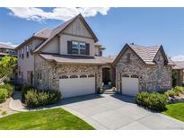 Beautiful two-story home featuring a well-manicured lawn, a three-car garage, and a stone and stucco facade at 10590 Soulmark Way, Highlands Ranch, CO 80126