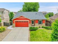 Charming red home featuring a well-manicured lawn, brick accents, and an attached two-car garage at 5577 Jasper St, Denver, CO 80239