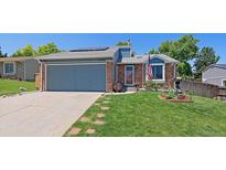 Charming single-story home with an attached garage, red brick accents, and lush green lawn at 6085 S Parfet St, Littleton, CO 80127