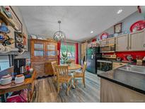 Eat-in kitchen features stainless steel appliances, black countertop, and hardwood floors at 6085 S Parfet St, Littleton, CO 80127