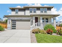 Charming two-story home with stone accents, a modern garage door, and landscaped front yard at 6558 Kenzie Cir, Castle Pines, CO 80108