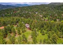 Expansive aerial view of home nestled amongst many trees in scenic mountain community at 28065 Camel Heights Cir, Evergreen, CO 80439